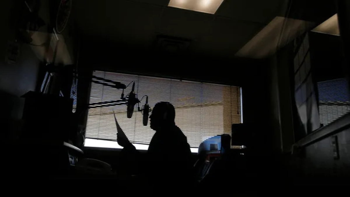 A photo of a radio host in a dark studio