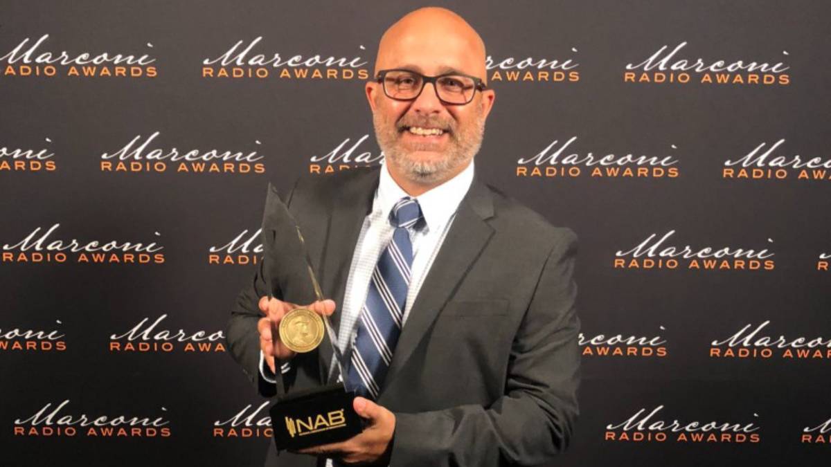 A photo of Mike Ragozino holding a Marconi Award