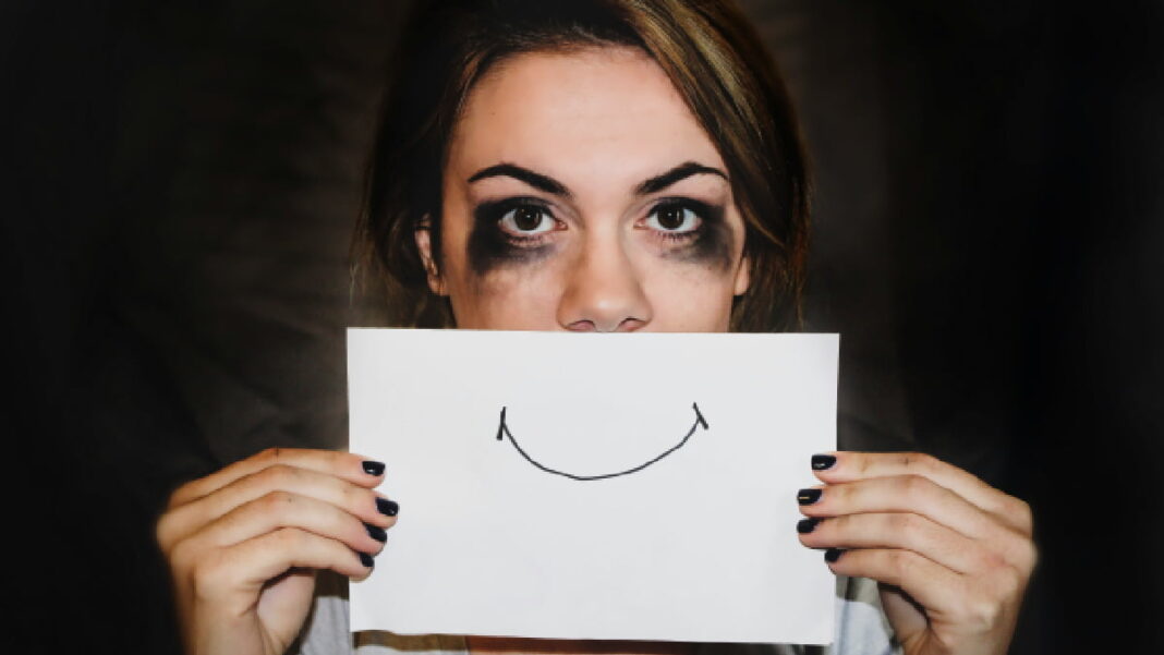 A photo of someone holding up a smiley face on a piece of paper to their face